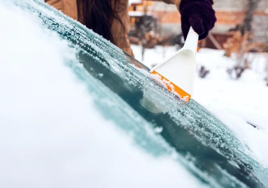 person scraping ice off of a windshield