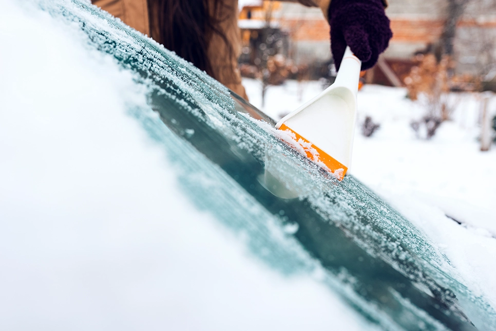 person scraping ice off of a windshield