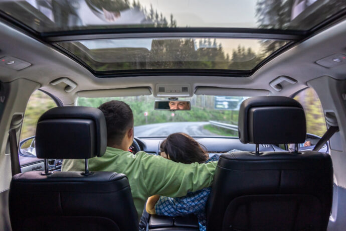 a couple driving in a vehicle with many windows