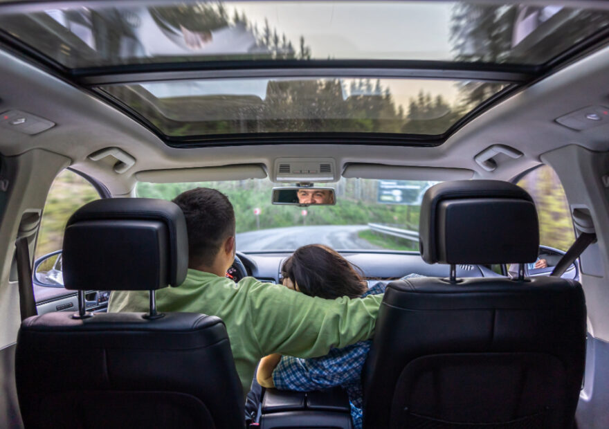 a couple driving in a vehicle with many windows