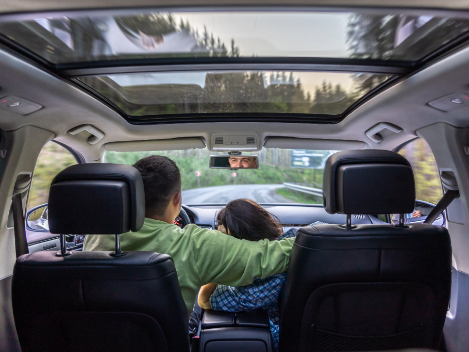 a couple driving in a vehicle with many windows