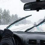 A driver using windshield wiper fluid to clean their windshield while driving.